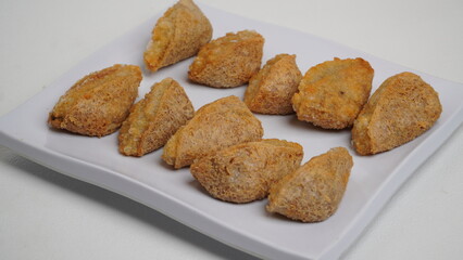 A plate of fried tahu walik is placed on a white base and background (isolated white).