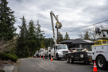 Heavy duty utility company hydraulic bucket lift trucks with line crew working on power lines and install new transformer and LED streetlight, residential power line maintenance and upgrade
