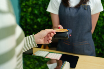 Customers pay with credit cards at fruit shop with small business owners. Contactless payment process captured as customer holds card to digital reader in a grocery store.