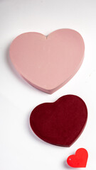 Three heart-shaped objects in different sizes and colors, including red, pink, and burgundy, placed on a white background, symbolizing love, romance, and affection for Valentine's Day