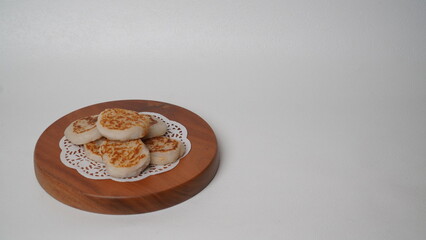 Wingko babat is served using a brown container made of wood and placed on a white background (isolated white).