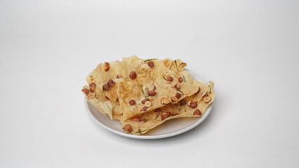 Some peanut brittle served on a white plate and placed on a white background (isolated white).