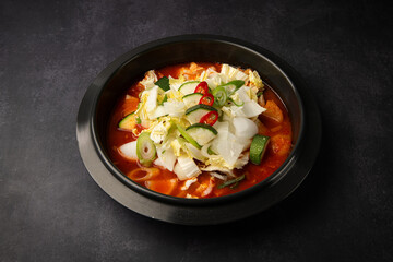 Korean spicy miso soup in bowl on dark background, top view