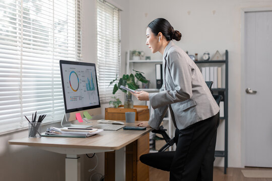 Young business finance market analyst in standing working at office  .Business woman analyze document Graphs and diagramm on Desktop Computer screen.
