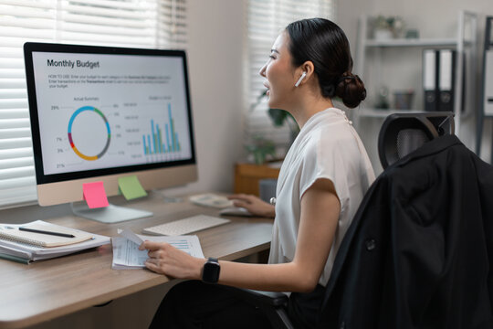 Young business finance market analyst in eyeglasses working at office  .Business woman analyze document Graphs and diagramm on Desktop Computer screen.
