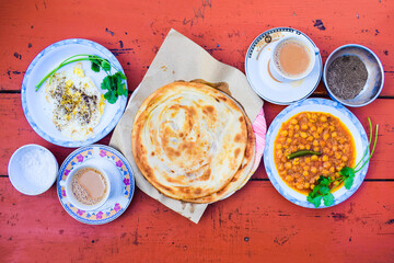 Pakistani traditional breakfast paratha bread and fried scrambled eggs omelet with spices, choly baratha, Milk tea fried egg