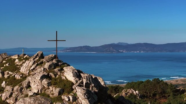 Wooden Cross Atop Rocky Hill In Porto do Son, A Coruna, Spain. aerial orbiting shot