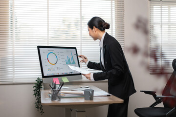 Business woman data analyst using calculator anddesktop computer for do math finance on wooden...