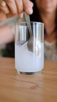 Middle age woman mixing creatine powder with water. Vertical shot.