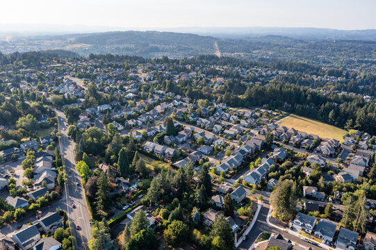 Aerial drone view of Tigard, Oregon, showcasing suburban neighborhoods, tree-lined streets, commercial areas, parks, and roads, with a mix of residential and business districts in the Portland metro  