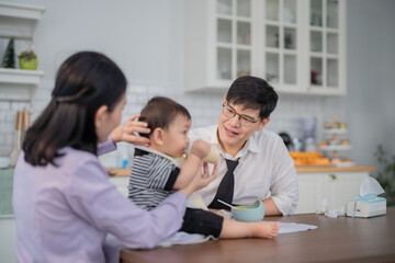 Fototapeta premium Caregiver feeding toddler in a bright kitchen setting with mother assisting during a mealtime