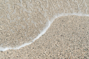Summer beach sand, blue waves and white foam