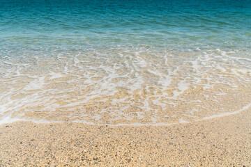 Summer beach sand, blue waves and white foam