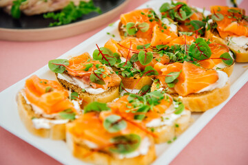 Delicious bruschetta with salmon on a white plate. Salmon toast with cream cheese and microgreens. Healthy food, health benefits, omega 3, fish oil. Natural, delicious and healthy seafood