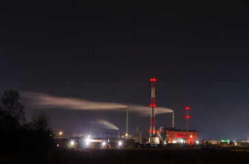 Iindustrial factory emitting smoke into the dark night sky with glowing lights. Smoke drifting, moody, long exposure, industrial zone, environmental impact, night photography, illuminated chimneys,
