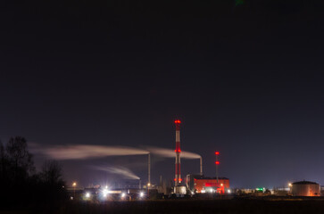 Iindustrial factory emitting smoke into the dark night sky with glowing lights. Smoke drifting, moody, long exposure, industrial zone, environmental impact, night photography, illuminated chimneys