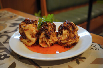 Close up of Dumplings poured with chili oil served on a white plate on the restaurant table