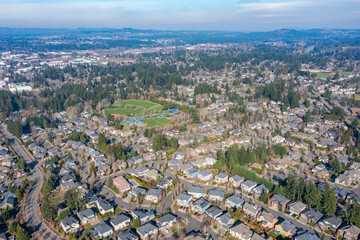 Aerial drone view of Tualatin, OR, showcasing an expansive residential neighborhood with tree-lined streets, suburban homes, parks, and green spaces, highlighting the area's planned community layout