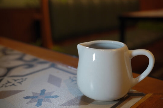 Small ceramic sugar syrup jug on wooden table