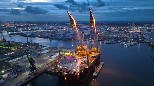 Rotterdam, Netherlands. Drone flight over industrial area with cargo ports, containers and a semi-submersible ship, heavy lifting crane. Machines designed for work at sea