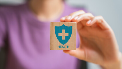 Hand holding wooden block with medical and shield icons, Health insurance concept.