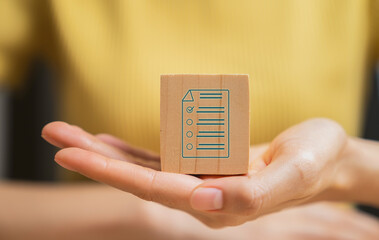 Hand holding wooden block and filling survey form online.