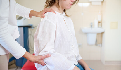 Physical therapist doing chiropractic adjustment on shoulder of patient in treatment office room. Osteopathic medicine and physiotherapy concept. Crop view