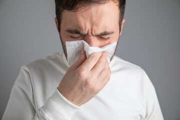 Caucasian sick man blowing his nose.