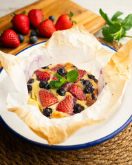 Delicious sweet clafoutis tart with blueberries and strawberries baked using a traditional French recipe.