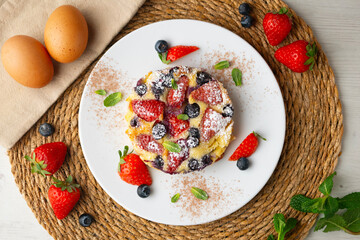 Delicious sweet clafoutis tart with blueberries and strawberries baked using a traditional French recipe.