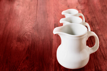 White ceramic jugs on red background