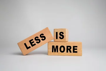 less is more words symbol on wooden block isolated on white background. motivational quote concept