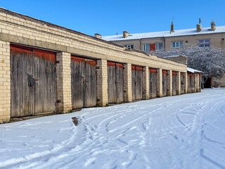 Fototapeta premium old stone garages with wooden doors in winter, in the background is an apartment house in Latvia