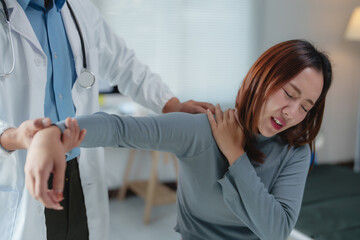 Female patient experiencing shoulder pain during a physical examination conducted by a male doctor...
