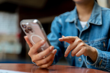 Close up shot of a hand holding a smartphone with left hand and pointing at screen with right hand.