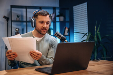 By the laptop. Man with microphone in the studio, conception of podcast