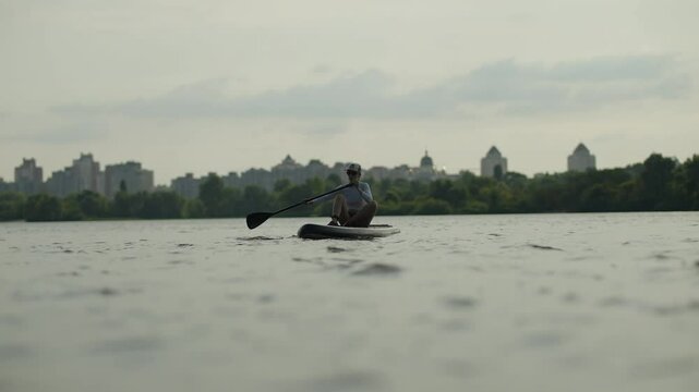 Paddling on Stand Up Paddleboard in River. Surfer Balancing on SUP Board during Sunset