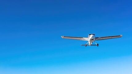 Obraz premium A small airplane flying high in a cloudless blue sky.