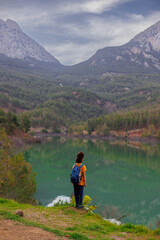Fototapeta premium summer camp. a boy with a backpack looks at a beautiful mountain lake. trekking near a mountain lake.