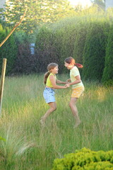 Fototapeta premium In this enchanting summer scene, friends and sisters are joyfully playing together under the warm raindrops. Their laughter fills the air as embrace the refreshing rain