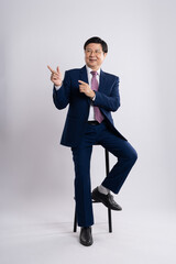 Portrait of an elderly businessman sitting in a chair on a white background