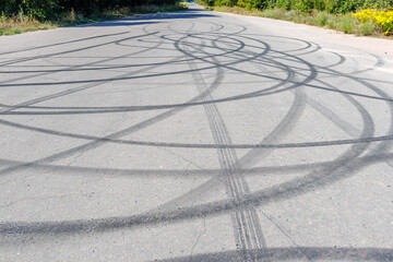 Skid marks on the road surface. Circular tire tracks left by drivers making donuts. Tire print on...