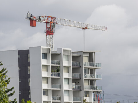 A construction crane during a building boom, highlighted against an overcast sky and positioned behind an apartment building on the Gold Coast in Queensland, Australia.