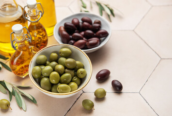 Bowls of green and black olives with olive oil bottles and olive branches