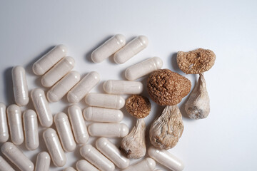 Alternative medicine supplements and dietary drugs for micro-dosing. Psilocybe Cubensis mushrooms on white studio background,close up. Psilocybin shrooms Golden Teacher with pills, medical capsules