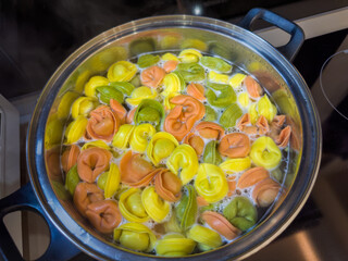 Multicolored meat dumplings during boiling in pot on a stove