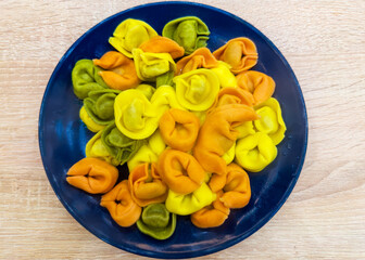 Heap of multicolored meat dumplings on blue dish, top view