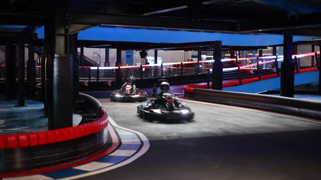 Child, driving go cart car in an indoor race track, enjoying sport racing
