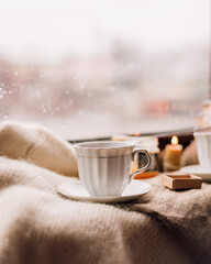 woman drinking tea from a white cup and saucer near the window, tea with honey, cozy composition, tea party by candlelight