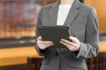 タブレットを持って店内を見るスーツを着た女性